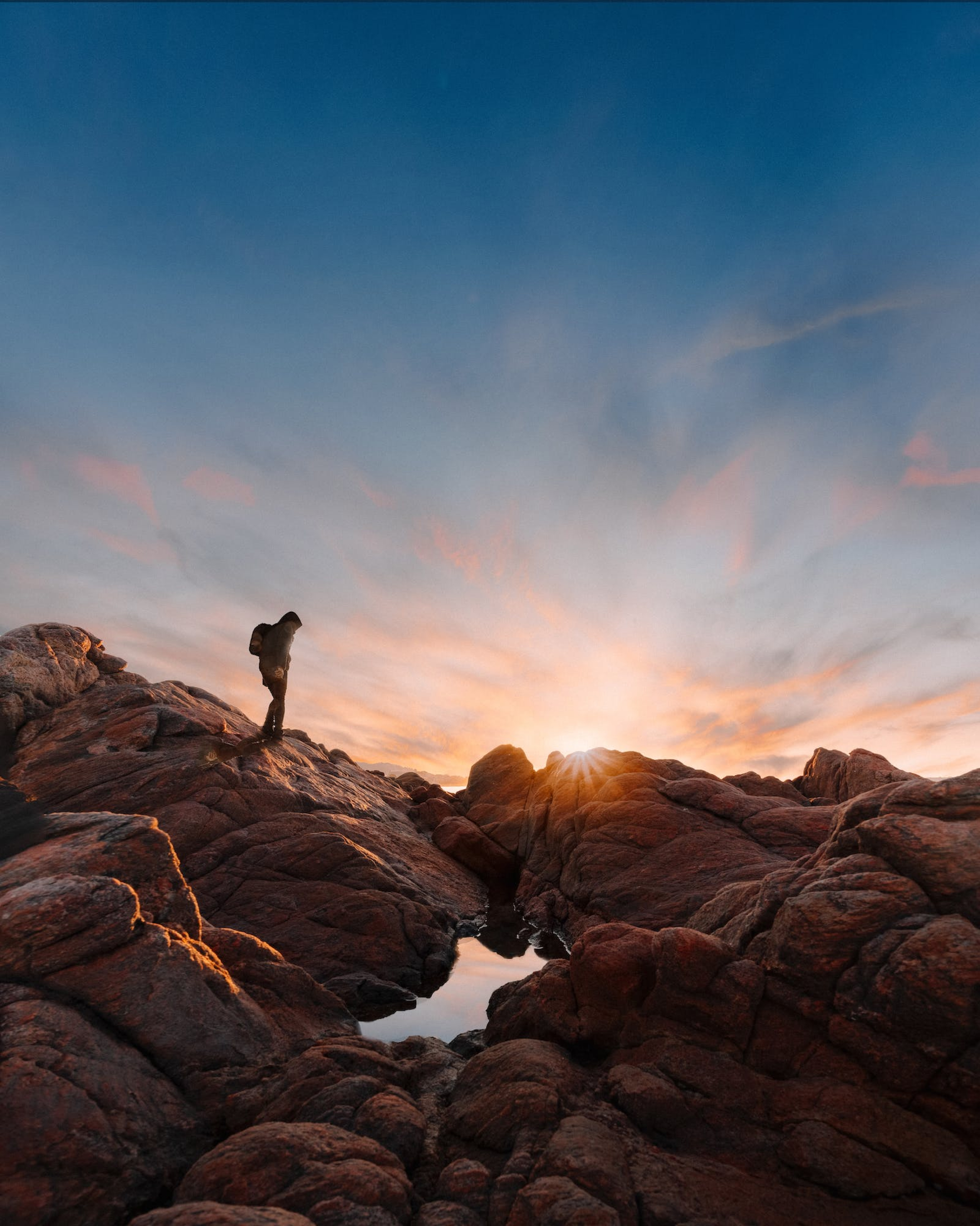 A person standing in rocky mountains at golden hour